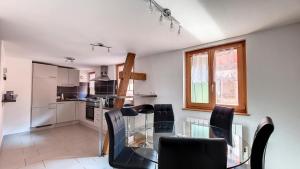 a kitchen and dining room with a glass table and chairs at Le Zen in Eguisheim