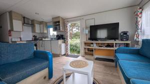 a living room with two blue couches and a tv at Abi static caravan close to Edinburgh in Port Seton
