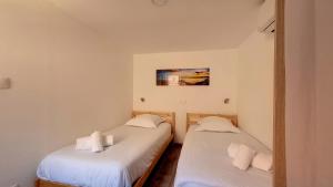 two twin beds in a room with white walls at Le Nature in Eguisheim