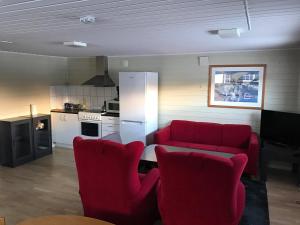 a living room with a red couch and a kitchen at Polar Hotel Oteren in Oteren