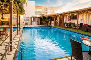 a swimming pool with tables and chairs next to a building at Grand Bohabs Hotel in Abuja
