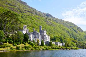 a castle on a hill next to a body of water at Roundstone Retreats Abbys cottage in Roundstone