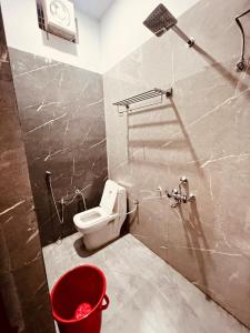 a bathroom with a toilet and a red bucket at ramraz residency in Ayodhya