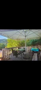 a table and chairs under a white umbrella at Perućac - Apartman sa pogledom na jezero in Perućac +9 photos