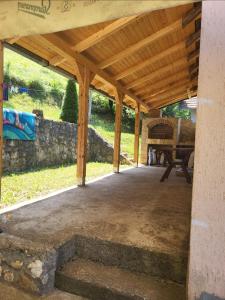 a wooden pavilion with a picnic table and a stone wall at Perućac - Apartman sa pogledom na jezero in Perućac