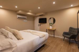 a bedroom with a bed and a chair and a television at Arena Málaga Suites in Málaga