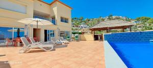 a house with a swimming pool and chairs and an umbrella at Villa Evora in Moraira