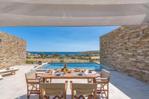 a dining room with a table and chairs and a pool at Gray and Blue in Andros