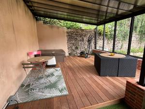 a screened in porch with two tables and a stone wall at La halte du Clos in Souvigny