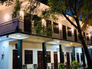 a building with a balcony with chairs and a tree at Quench Inn in Ampara