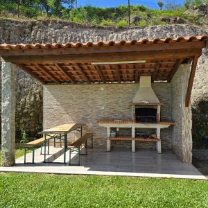 a patio with a picnic table and an outdoor oven at Casa da Batoca - Rossas in Vieira do Minho