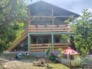 a house with a woman sitting on the porch of it at Apartman Dunav Plus in Donji Milanovac
