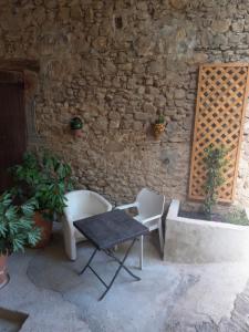 a table and chairs in front of a stone wall at Comfortable Village Apartment in Barbieres with access to large garden with beautiful views in Barbières