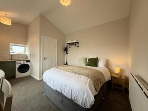 a bedroom with a bed and a washing machine at The Den- Cosy Studio in Dowlais