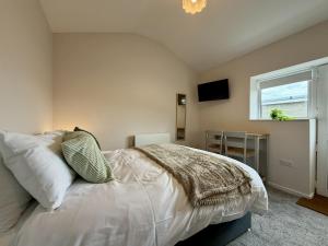 a bedroom with a bed with white sheets and a window at The Den- Cosy Studio in Dowlais