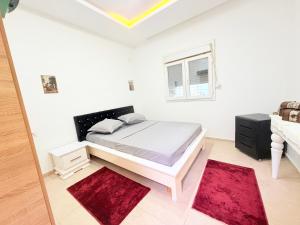 a white bedroom with a bed and red rugs at Résidence Azur Djerba in Taguermess +32 photos