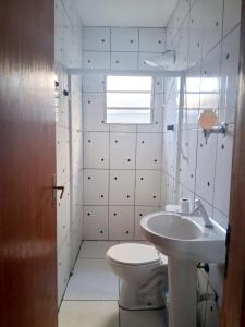 a white bathroom with a toilet and a sink at Hospedagem Aeroporto in Campinas