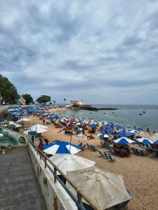 a beach with many blue and white umbrellas and people at Aconchego das Borboletas in Salvador