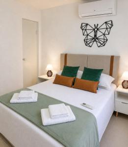 a bedroom with a large bed with two towels on it at Aconchego das Borboletas in Salvador