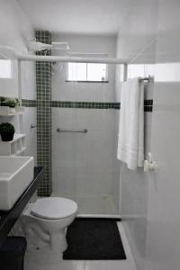 a white bathroom with a shower and a toilet at Aconchego das Borboletas in Salvador