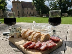 a wooden table with two glasses of wine and food at Chateau d Albon - Catherine de Medicis in Saint-André-dʼApchon