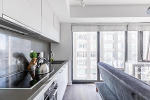a kitchen with white cabinets and a large window at The Nobleton Suites - Yorkville in Toronto