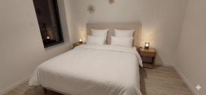 a bedroom with a large white bed with two night stands at Klass Loft Kemperle in Quimperlé