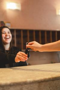 a woman is handing a person a car key at Hotel Alles Blau in Pelotas