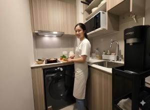 a woman standing in a kitchen with a dishwasher at The Rock Condo Central Phuket "Min-1 week" in Ban Rangeng