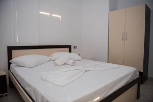 a bed with white sheets and two pillows at Seaview Radhime in Vlorë