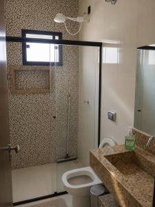 a bathroom with a toilet and a glass shower at Pousada Emanuel in Paracatu
