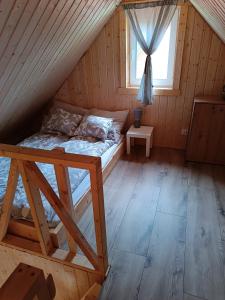 a bed in a wooden room with a window at Domki Marianowo in Marianowo