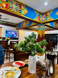 a table with plates of food and a vase with flowers at Arhat Resort in Deskit
