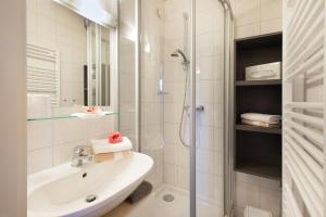 a white bathroom with a shower and a sink at Haus Elisabeth, Appartements in Krumpendorf am Wörthersee