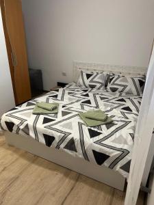a bed with a black and white comforter and green pillows at Raisa in Ocna Sibiului
