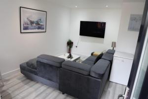 a living room with a black couch and a tv at Comfy Guest suite in Dartford