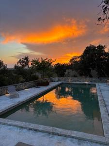 a swimming pool with a sunset in the background at Le jardin suspendu in Gordes