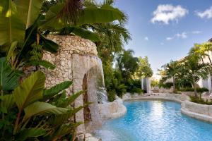 a swimming pool with a waterfall in a resort at Blue Monkey Hotel & Beach Club in Saint James