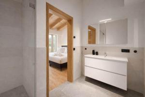 a bathroom with a sink and a mirror and a bed at SKYLINE Chalet - Two-Level Penthouse with Private Whirlpool in Mühlen