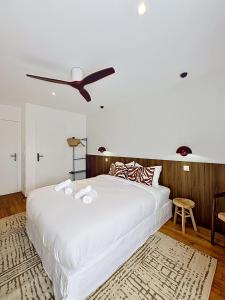 a bedroom with a large white bed with a ceiling fan at Maison Plage - boutique hôtel in Saint-Brevin-les-Pins