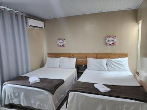 two beds sitting next to each other in a room at Pousada King in Vitória da Conquista