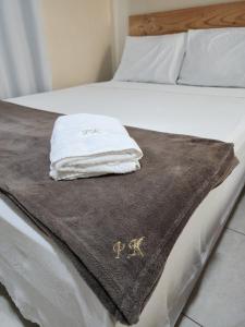 a bed with a brown blanket and white towels on it at Pousada King in Vitória da Conquista