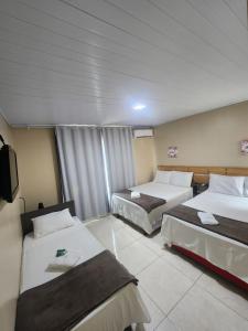 a hotel room with two beds and a tv at Pousada King in Vitória da Conquista