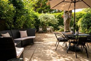 a patio with a table and chairs and an umbrella at Beautiful New Forest Hideaway in West Wellow