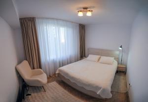 a bedroom with a bed and a chair and a window at Shakespeare Central Apartment in Craiova