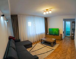 a living room with a couch and a flat screen tv at Shakespeare Central Apartment in Craiova