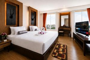 a bedroom with a large bed and a flat screen tv at Aiyara Palace in North Pattaya