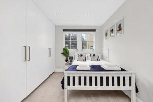 a white bedroom with a bed and a window at Flat in Lambeth in London