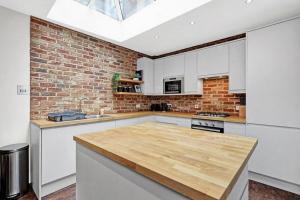 a kitchen with white cabinets and a brick wall at Flat in Lambeth in London
