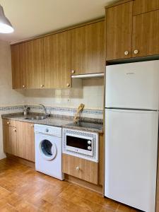 a kitchen with a washing machine and a refrigerator at Rincón de Laciana in Caboalles de Abajo